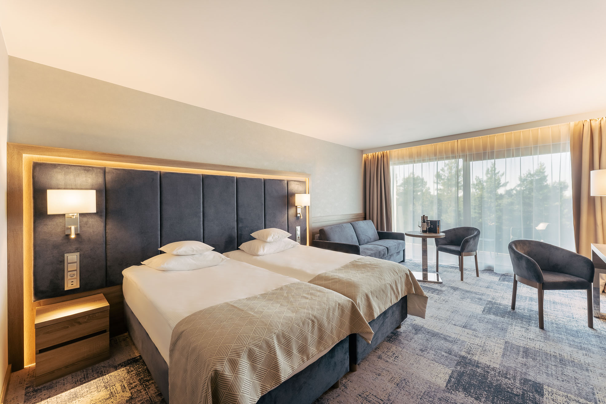 Hotelzimmer mit anthrazitfarbener Kopfteilwand und hinterleuchtetem Holzrahmen